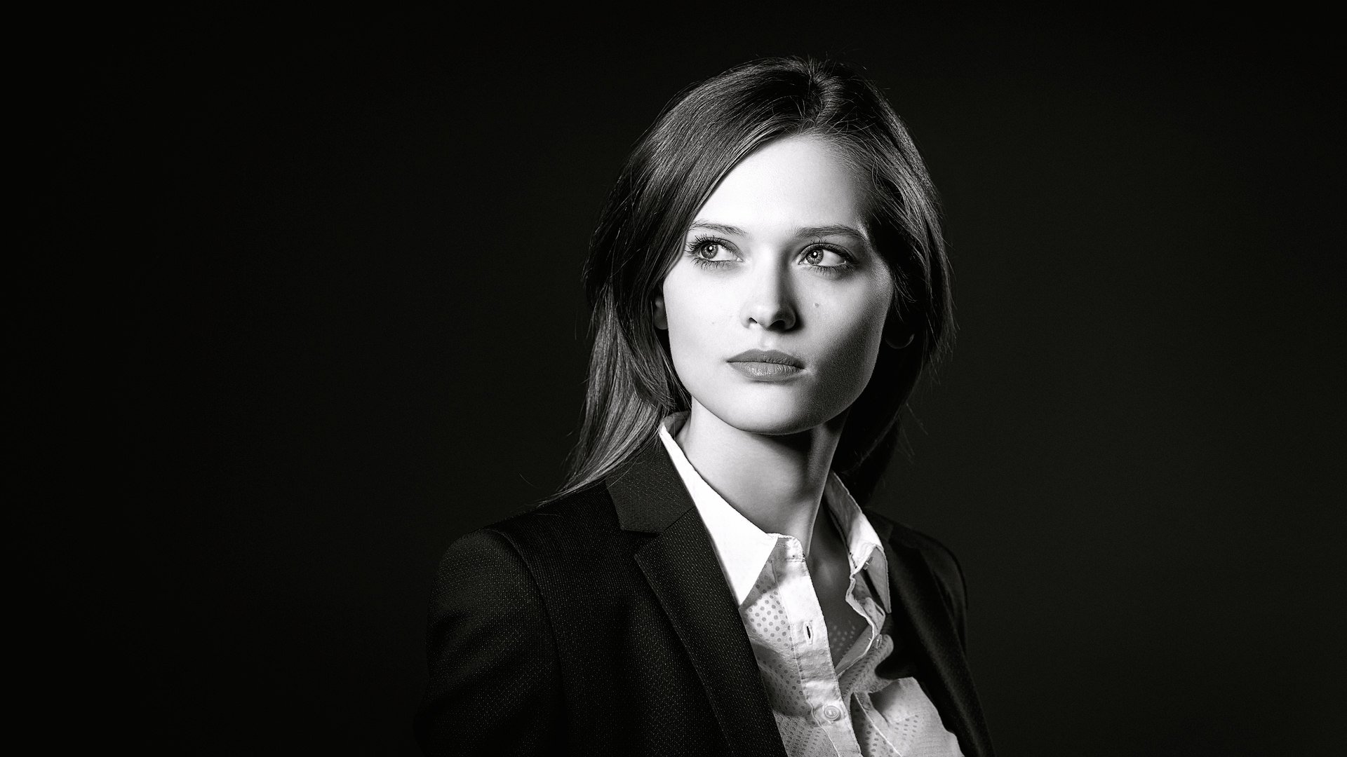Black and white HD desktop wallpaper featuring a close-up portrait of a female model with a serious expression against a dark background.