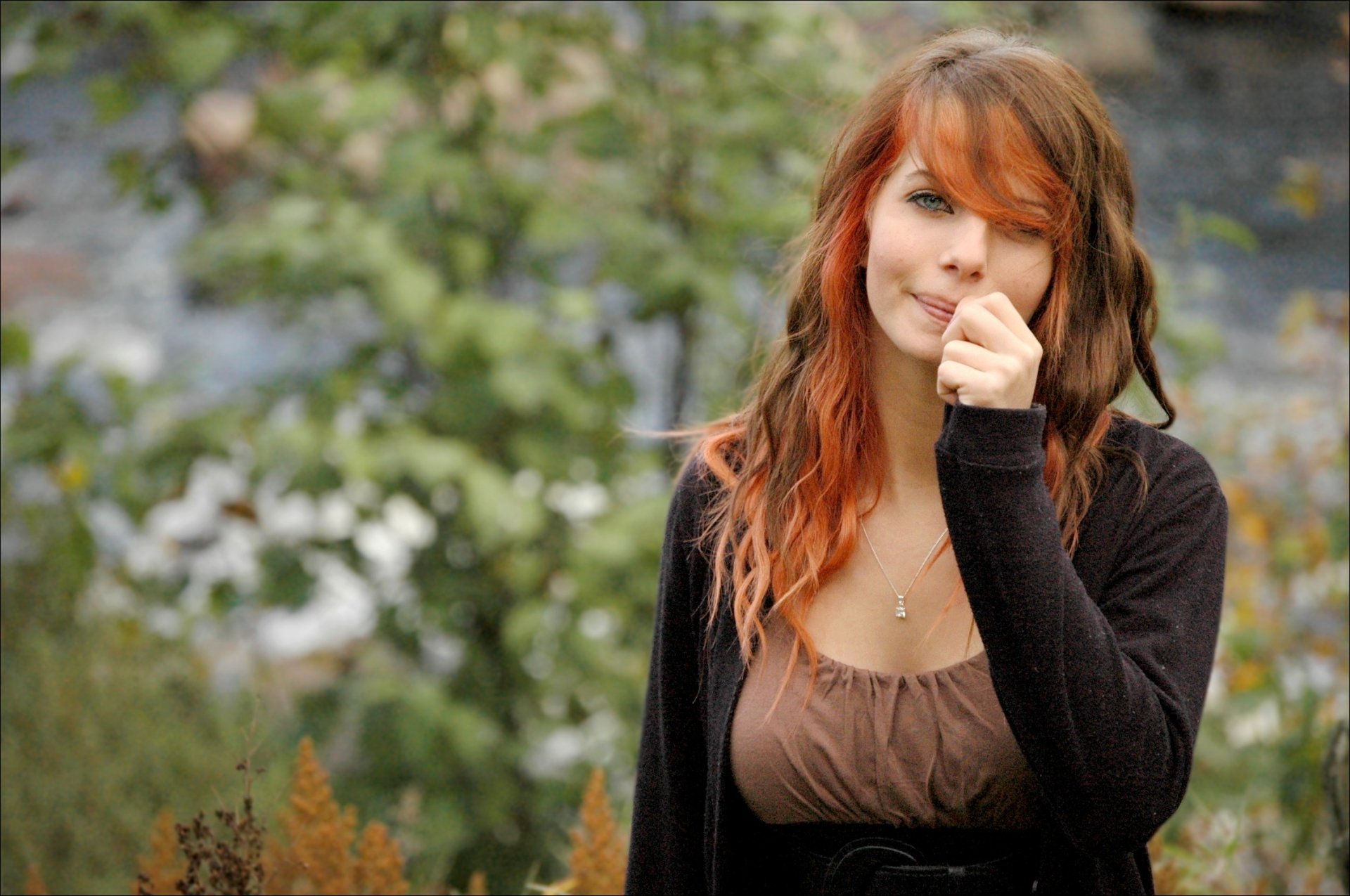 HD desktop wallpaper featuring a model with red-tinted hair in an outdoor setting, surrounded by greenery and a blurred, natural background.