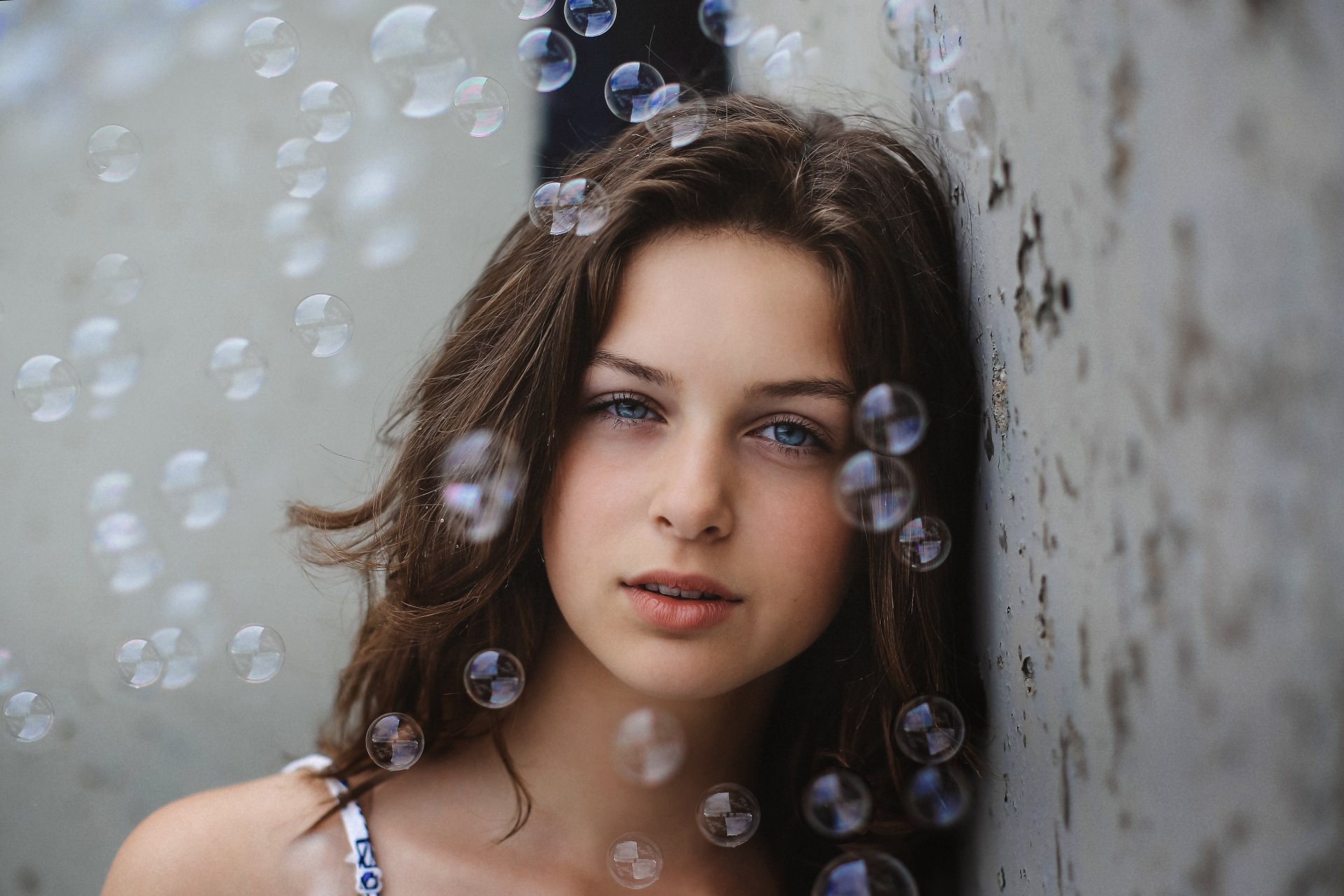 A brunette woman with blue eyes gazes thoughtfully, surrounded by shimmering bubbles, creating a captivating atmosphere in this 4K Ultra HD desktop wallpaper.