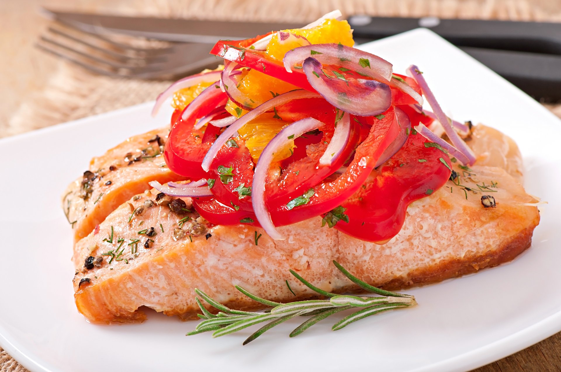 A vibrant seafood dish featuring a seasoned salmon fillet topped with colorful sautéed vegetables on a white plate, captured in 4K Ultra HD detail.