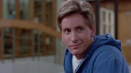 HD PC desktop wallpaper featuring Emilio Estevez as Andrew Clarke from the movie The Breakfast Club, smiling in a casual blue hoodie against a blurred indoor background.