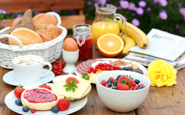 A vibrant 4K Ultra HD desktop wallpaper featuring a breakfast spread with fresh blueberries, strawberries, cheese, biscuits, orange juice, and a soft-boiled egg on a wooden table.