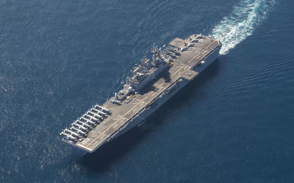 Aerial view of the USS Makin Island (LHD-8), a military amphibious assault ship and aircraft carrier, sailing in open sea captured in 4K Ultra HD quality.