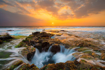 HD PC desktop wallpaper and background: golden sunset over ocean horizon, waves rushing into Thor's Well amid rocky tidepools, vivid sky reflecting on glistening water.