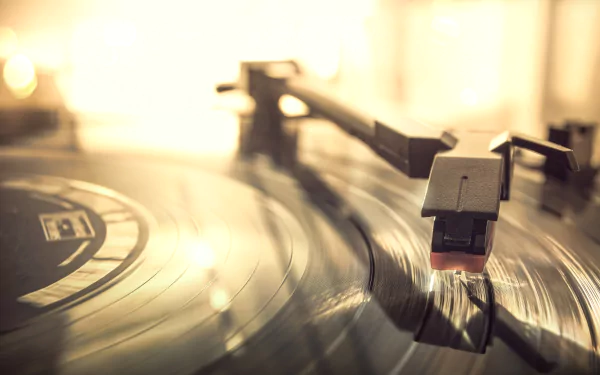 Close-up of a music record and stylus on a turntable with warm bokeh light — 5K Ultra HD PC desktop wallpaper and background.