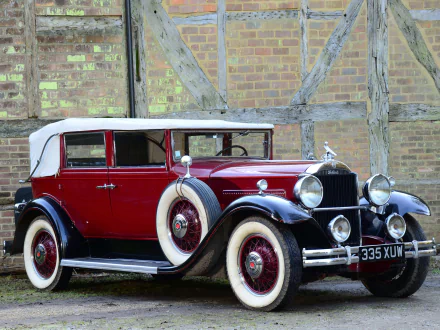 A vintage 1931 Packard Standard Eight Convertible Sedan in red and black, showcased against a rustic brick and timber wall, captured as an HD desktop wallpaper.