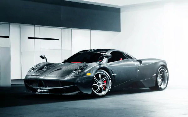 A sleek black Pagani Huayra supercar displayed in a modern garage, captured in stunning 4K Ultra HD as a striking PC desktop wallpaper.
