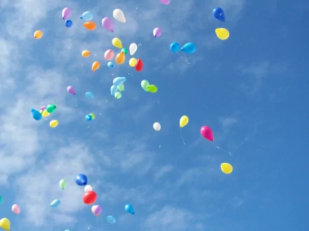 A vibrant array of colorful balloons floats against a clear blue sky, captured in this HD photography wallpaper, adding a cheerful touch to any desktop background.