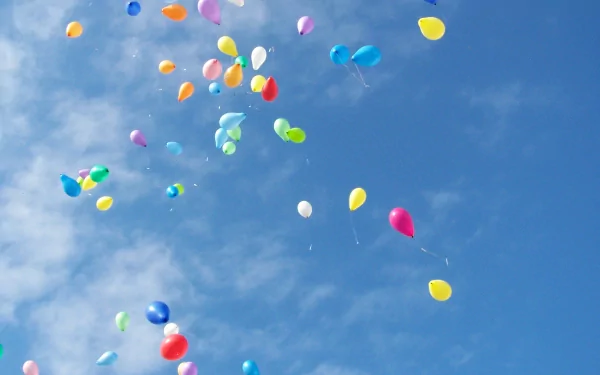 A vibrant array of colorful balloons floats against a clear blue sky, captured in this HD photography wallpaper, adding a cheerful touch to any desktop background.
