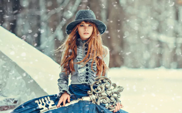 A redhead model in a chic dress and hat holds a large, ornate key amidst a winter snowfall, capturing an enchanting scene in this HD desktop wallpaper.