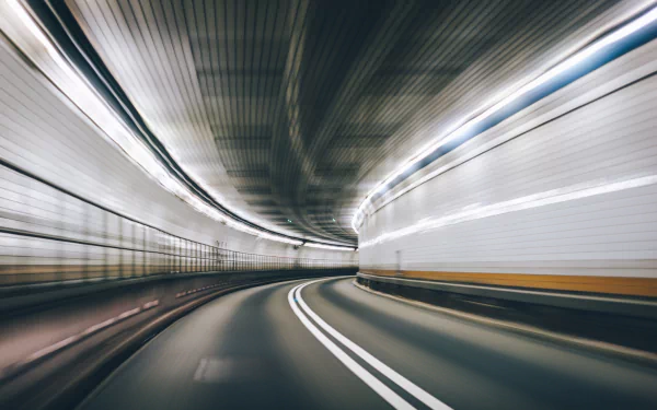 HD desktop wallpaper depicting a man-made tunnel with motion blur effects along a curved road, creating a dynamic and futuristic visual experience.