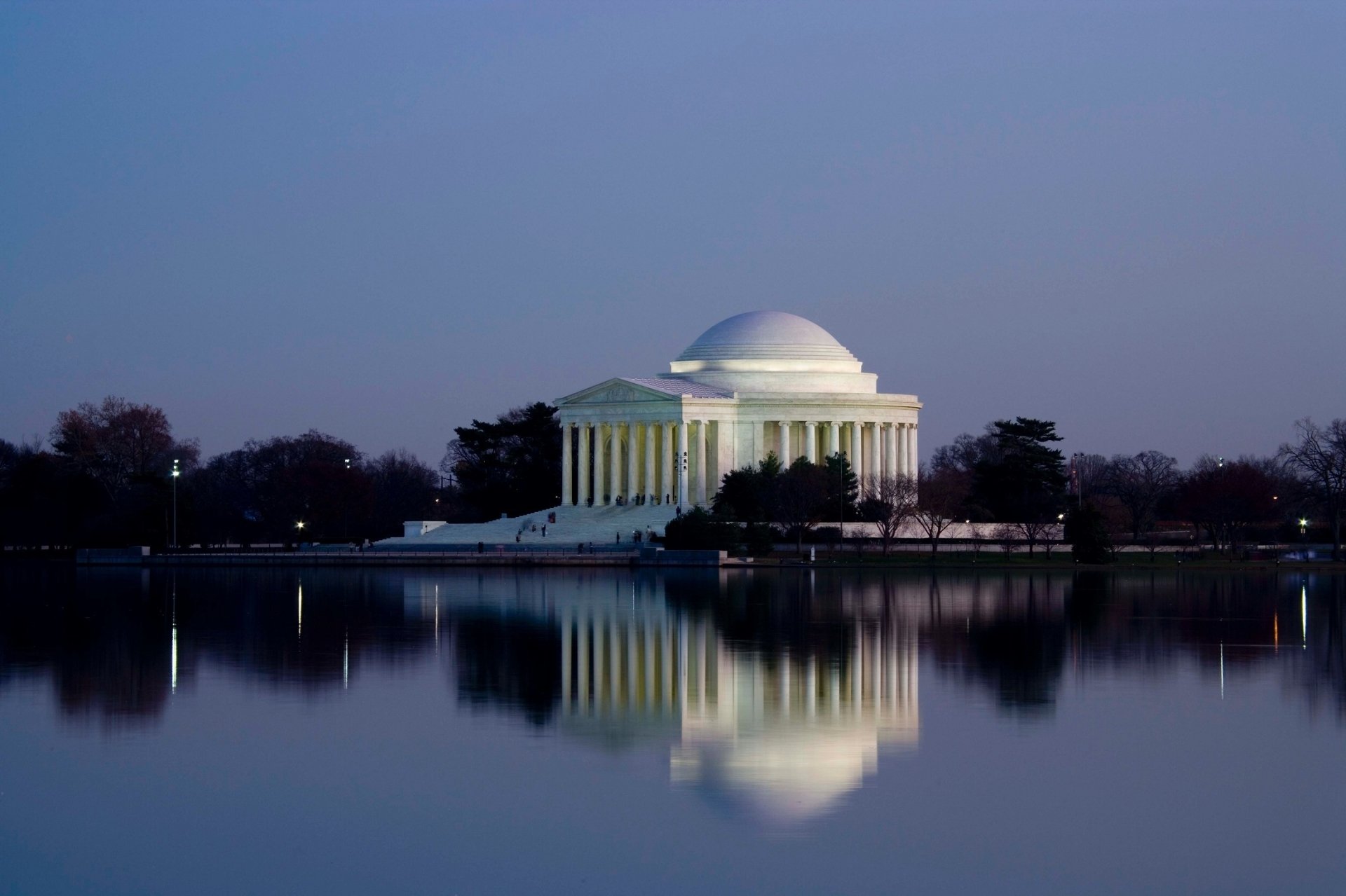 Twilight view of the historic Thomas Jefferson Memorial in Washington, USA, with its dome and architecture reflected in the calm lake water.