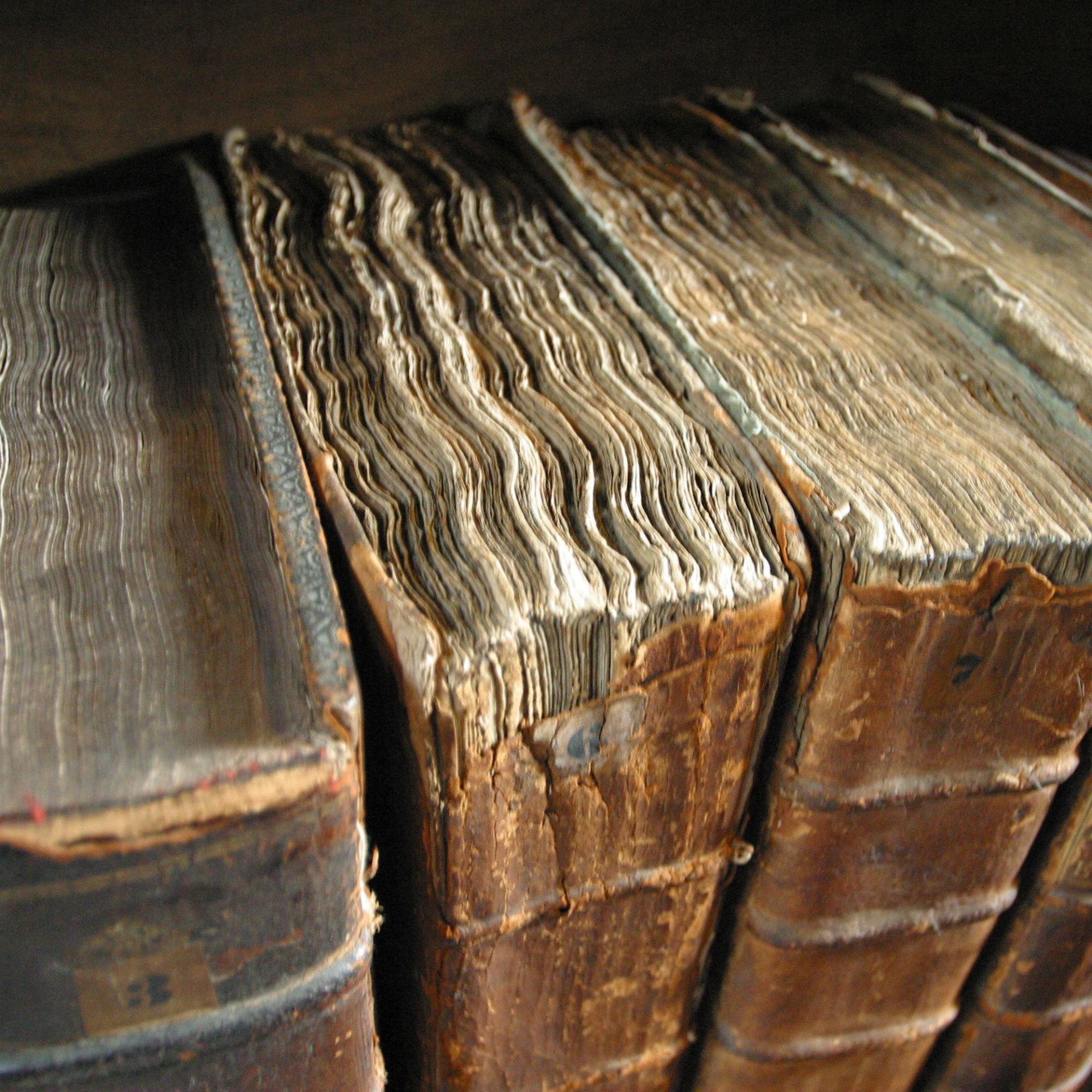 A close-up view of worn, antique books showcasing their textured pages and aged covers, providing an engaging backdrop for a desktop wallpaper.