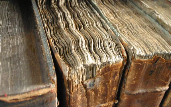 A close-up view of worn, antique books showcasing their textured pages and aged covers, providing an engaging backdrop for a desktop wallpaper.