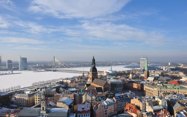 HD PC desktop wallpaper and background: panoramic Riga, Latvia skyline along the river with a man-made cable-stayed bridge and a mix of historic and modern architecture beneath a blue sky.