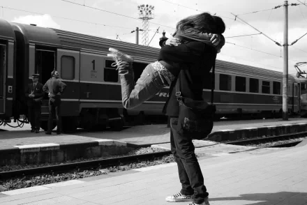 A black-and-white HD desktop wallpaper showing an emotional embrace on a train platform, capturing a heartfelt reunion moment.