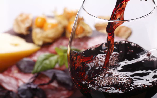 5K Ultra HD PC desktop wallpaper and background: red wine pouring into a glass beside cheese, cured meats and herbs — a crisp food and wine still life.
