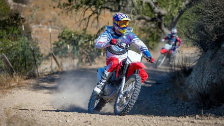 HD PC desktop wallpaper: rider on a red Honda CRF230F off-road vehicle (Honda CRF) kicking up dust on a sunlit trail, a second rider follows.