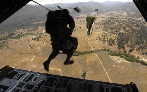 A paratrooper jumping from an aircraft over a vast, rugged landscape, captured as part of military operations. The image serves as an HD desktop wallpaper and background.