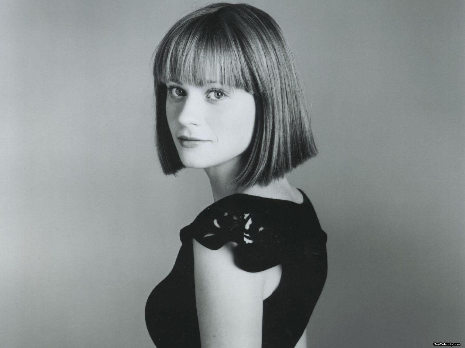 Black and white HD desktop wallpaper featuring celebrity Zooey Deschanel with a bob haircut, wearing a sleeveless black top, looking over her shoulder.