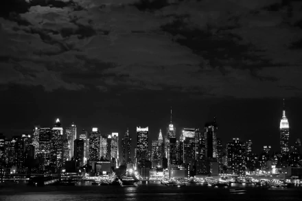Black and white 4K Ultra HD wallpaper showcasing the illuminated Manhattan skyline at night, highlighting New York's iconic man-made cityscape.