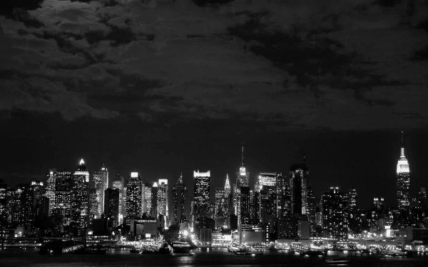 Black and white 4K Ultra HD wallpaper showcasing the illuminated Manhattan skyline at night, highlighting New York's iconic man-made cityscape.