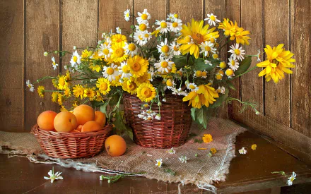 HD still life photography of yellow and white daisies arranged in a wicker vase, accompanied by a basket of fruit, set against a rustic wooden background.