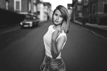 Black and white HD desktop wallpaper of a blonde female model posing confidently on a quiet urban street.
