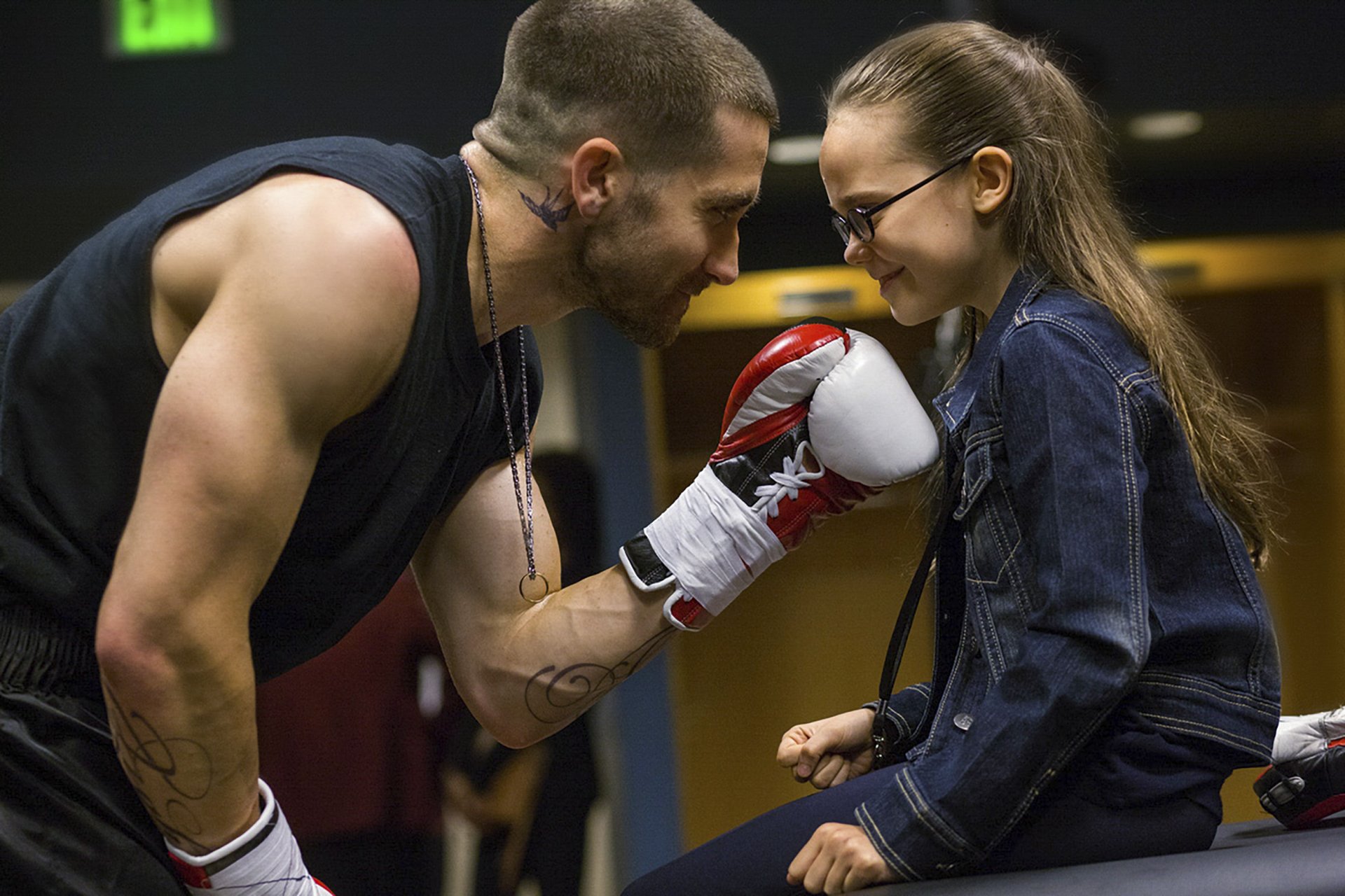 HD PC desktop wallpaper featuring Jake Gyllenhaal in a scene from the movie Southpaw, sharing a tender moment with a young girl wearing boxing gloves.
