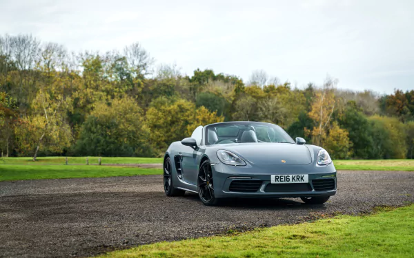 Silver Porsche Boxster parked on a gravel path with autumn trees in the background, captured in HD as a PC desktop wallpaper and background.