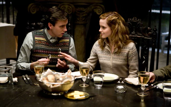 In this HD desktop wallpaper and background from Harry Potter and the Half-Blood Prince, Neville Longbottom (Matthew Lewis) and Hermione Granger (Emma Watson) are seen sharing a moment at a dining table.