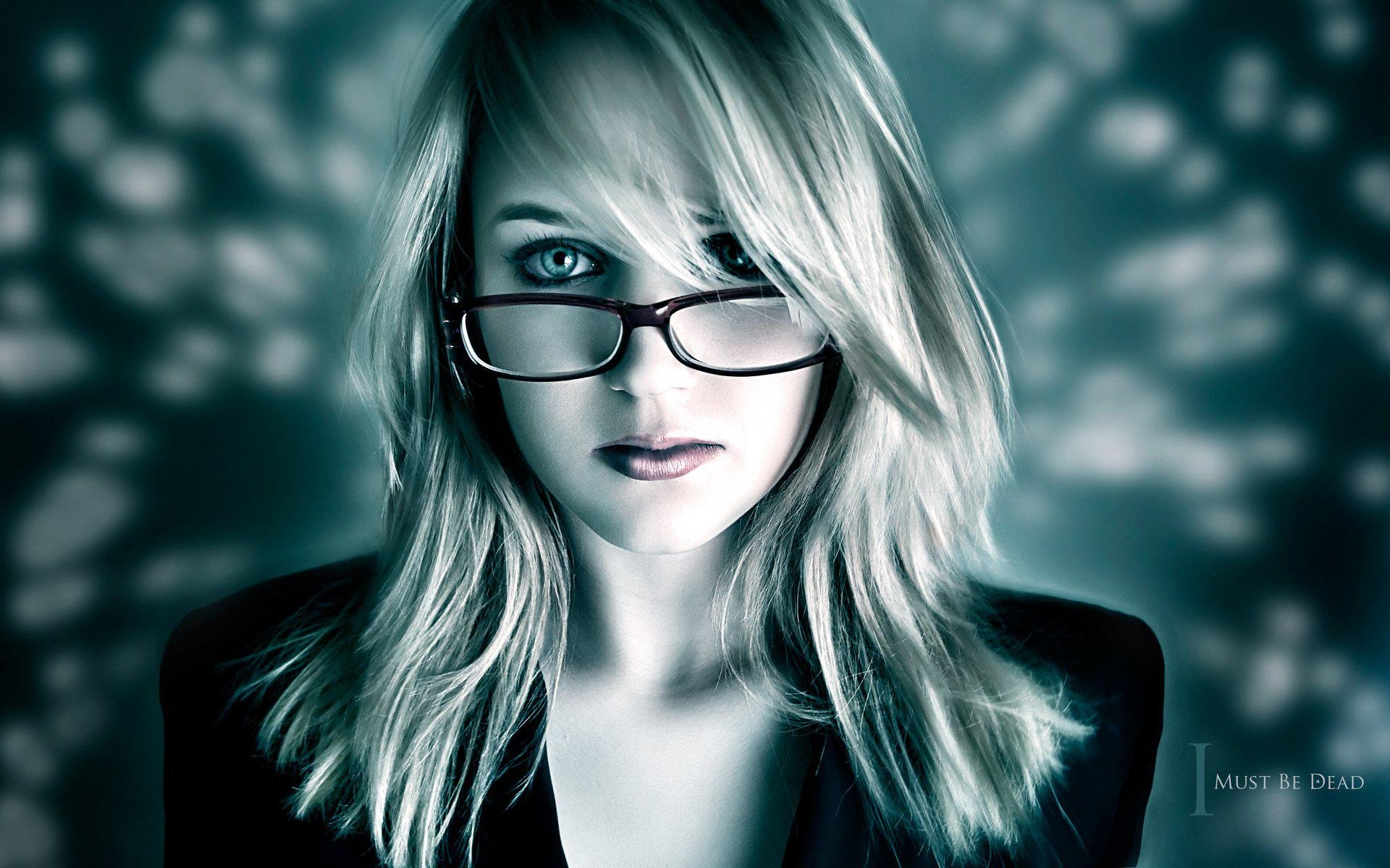 A woman with glasses stares intently at the camera, her blonde hair framing her face against a softly blurred, abstract background, creating a striking HD desktop wallpaper.