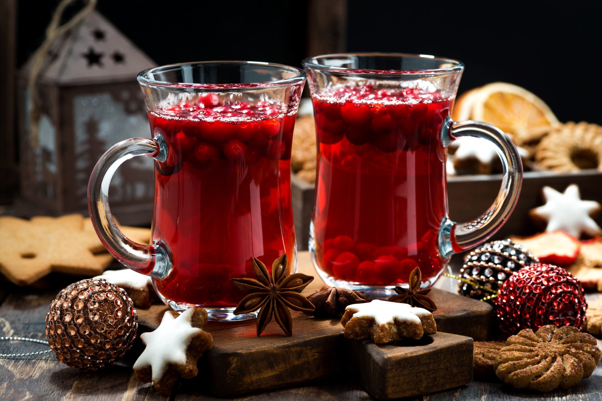 HD desktop wallpaper featuring a festive Christmas setup with two steaming mugs of red drink, surrounded by star anise, cookies, and holiday decorations.