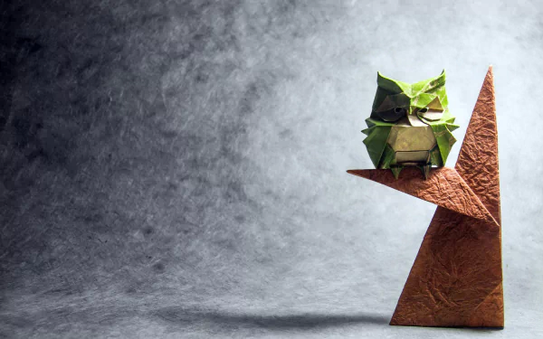 HD desktop wallpaper featuring a man-made origami owl perched on a geometric shape against a textured grey background.