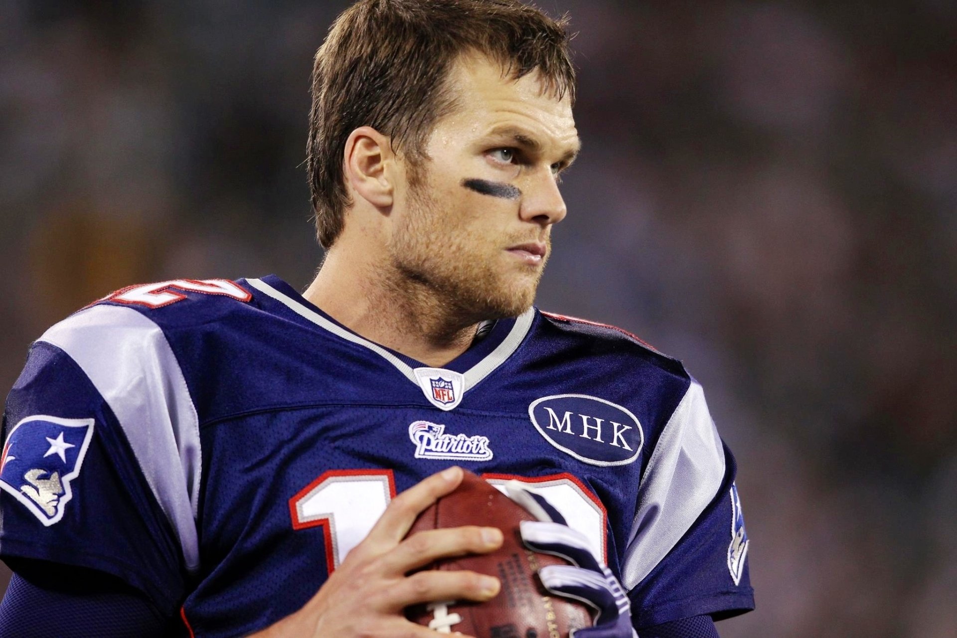HD Desktop wallpaper featuring a focused player in a New England Patriots jersey holding a football.