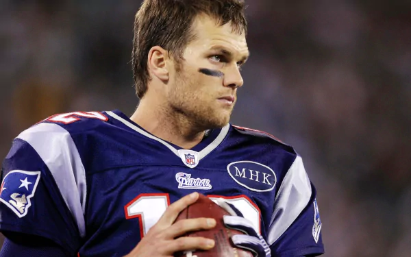 HD Desktop wallpaper featuring a focused player in a New England Patriots jersey holding a football.