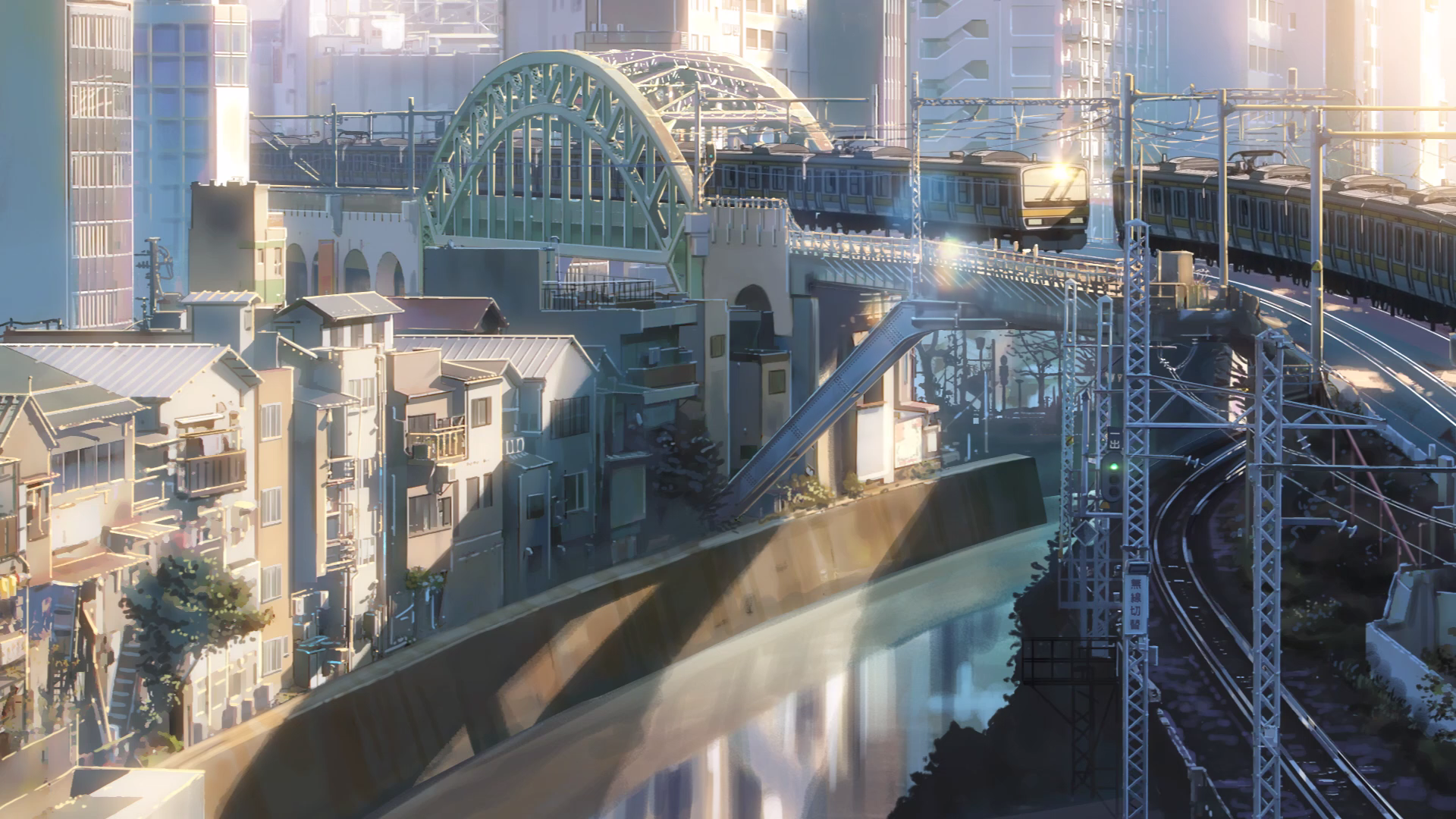 Anime-style HD PC desktop wallpaper of a detailed cityscape featuring a crossroad with a bridge, train tracks, and buildings bathed in soft sunlight.