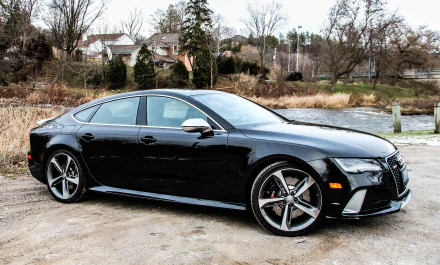 A sleek black Audi RS7 parked near a river, showcasing its sporty design and sharp lines in this 4K Ultra HD desktop wallpaper.