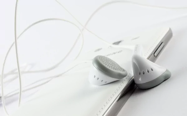 HD PC desktop wallpaper showing a white Samsung phone with white earbuds/headphones and tangled cord on a clean white background, music-themed.