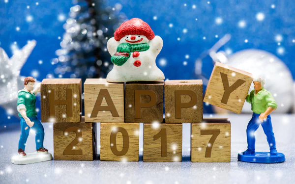 Festive New Year 2017 holiday 8K Ultra HD PC wallpaper: toy snowman and miniature figures with wooden blocks spelling HAPPY 2017 against a snowy blue bokeh background.