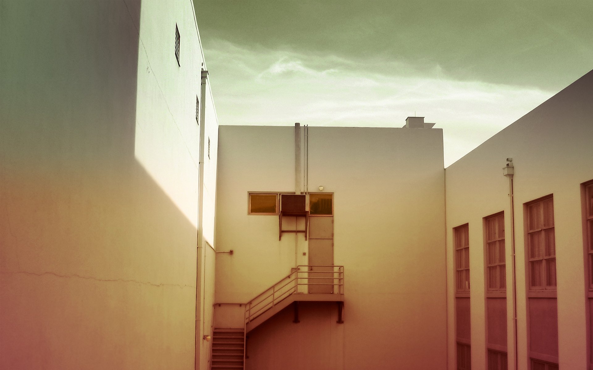 HD desktop wallpaper showcasing a man-made building with geometric shapes, staircases, and soft lighting under a cloudy sky.