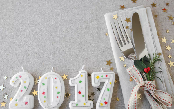 5K Ultra HD PC desktop wallpaper/background: candle digits 2017 with colorful confetti beside a tied holiday napkin and cutlery on a textured gray surface for New Year 2017 celebration.