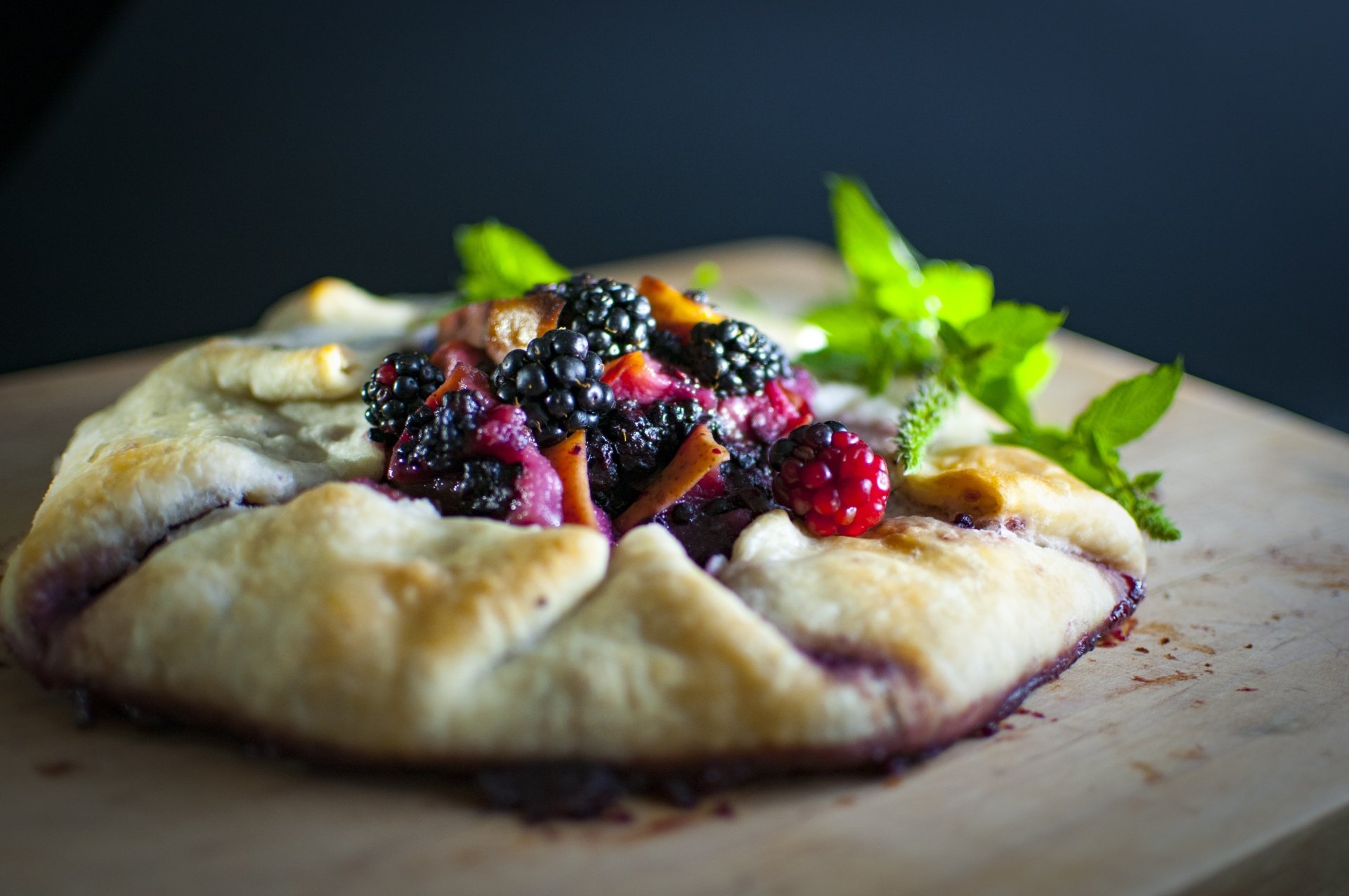 Close-up of a rustic berry galette with raspberries and blackberries on a wooden board — vibrant food baking scene, 4K Ultra HD PC desktop wallpaper/background