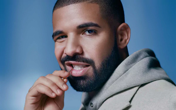HD desktop wallpaper featuring a portrait of a man with a beard and mustache, wearing a gray coat against a blue background.