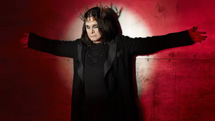HD PC desktop wallpaper of a heavy metal musician in a crown and dark robes, arms outstretched against a red-lit concrete wall.