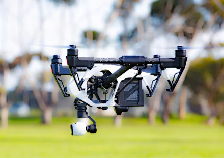 A high-definition desktop wallpaper showcasing a man-made drone hovering outdoors over a green field, emphasizing modern technology and innovation.