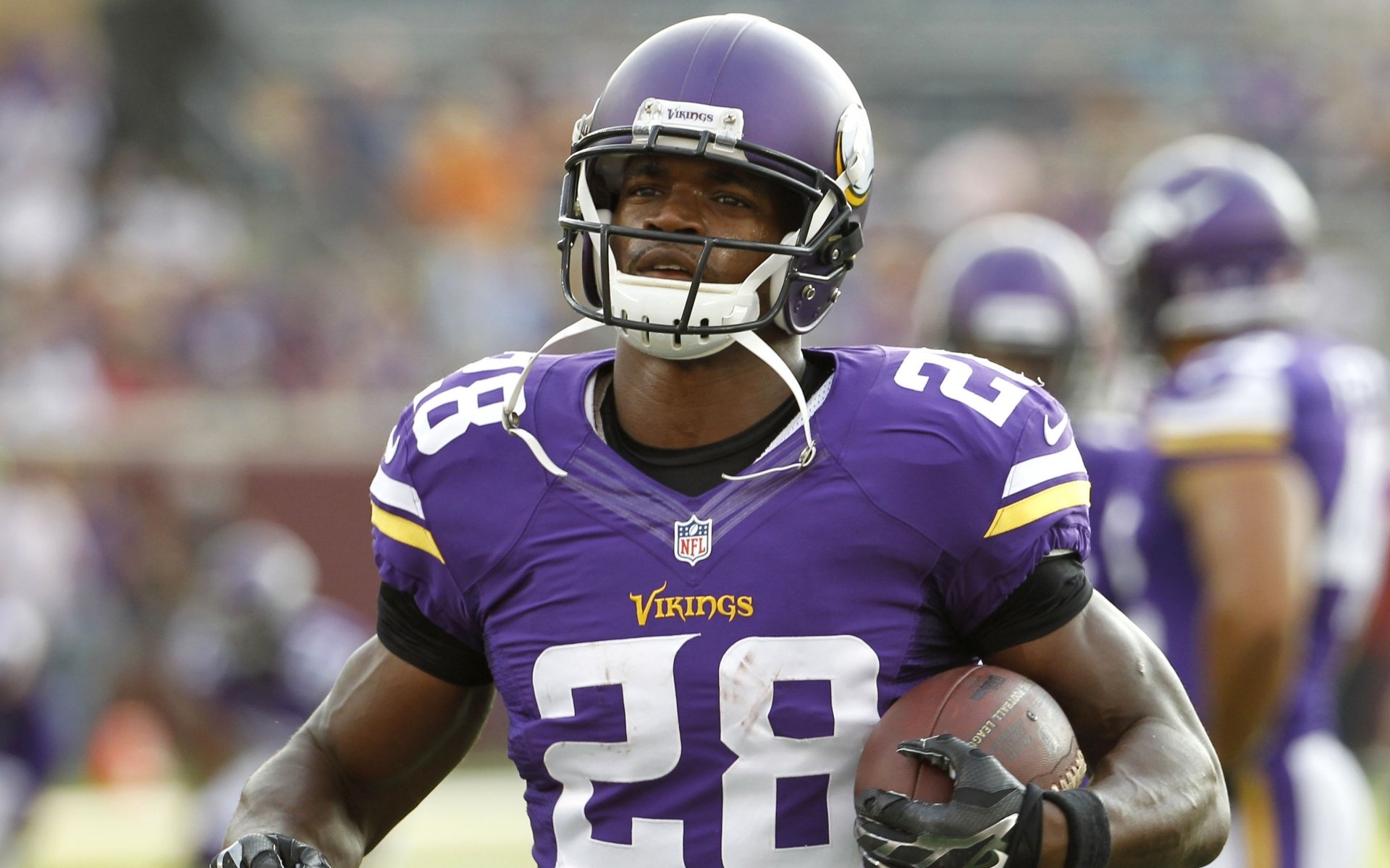 Adrian Peterson, wearing a Minnesota Vikings uniform, runs with a football, showcasing his prowess on the field in this HD sports wallpaper.