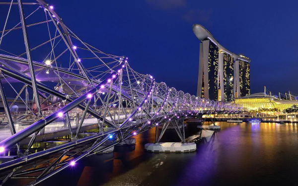 Night view of Singapore’s Helix Bridge illuminated in purple lights, reflecting on water with Marina Bay Sands glowing in the background.