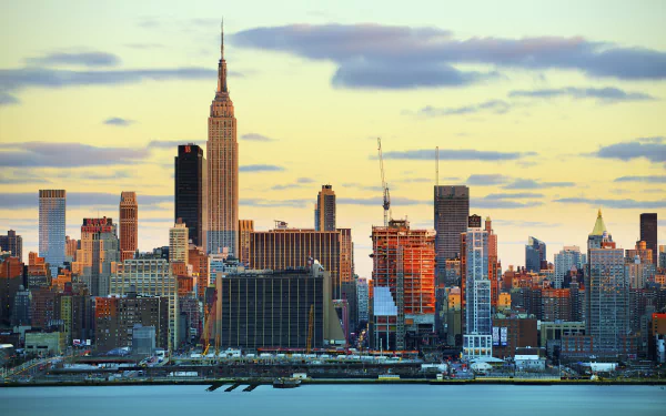 HD desktop wallpaper showing the Manhattan skyline with the iconic Empire State Building and surrounding skyscrapers in New York, USA during a colorful sunset.
