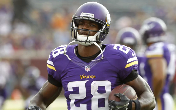 Adrian Peterson, wearing a Minnesota Vikings uniform, runs with a football, showcasing his prowess on the field in this HD sports wallpaper.